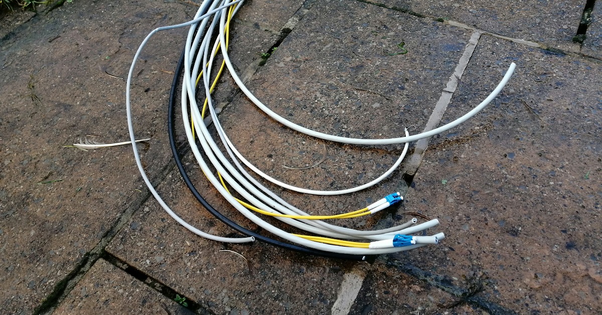 A bunch of cables lie on the ground, ready to be pulled through a duct.