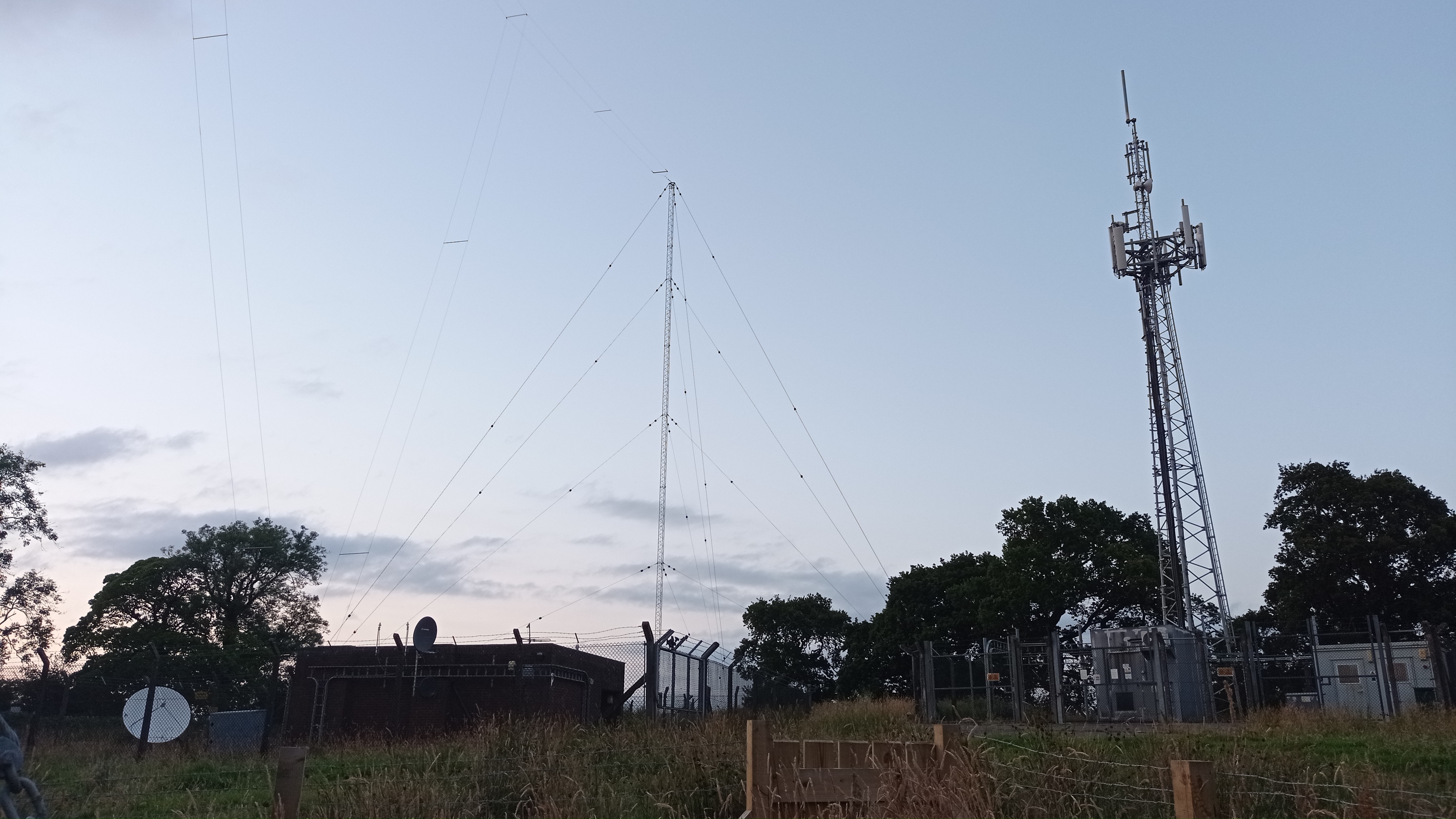 Wide view, showing the entire site. Towards the left, the long wire antenna for MW is visible - to the right, a freestanding tower carrying cellular antennas, and a colinear for DAB.