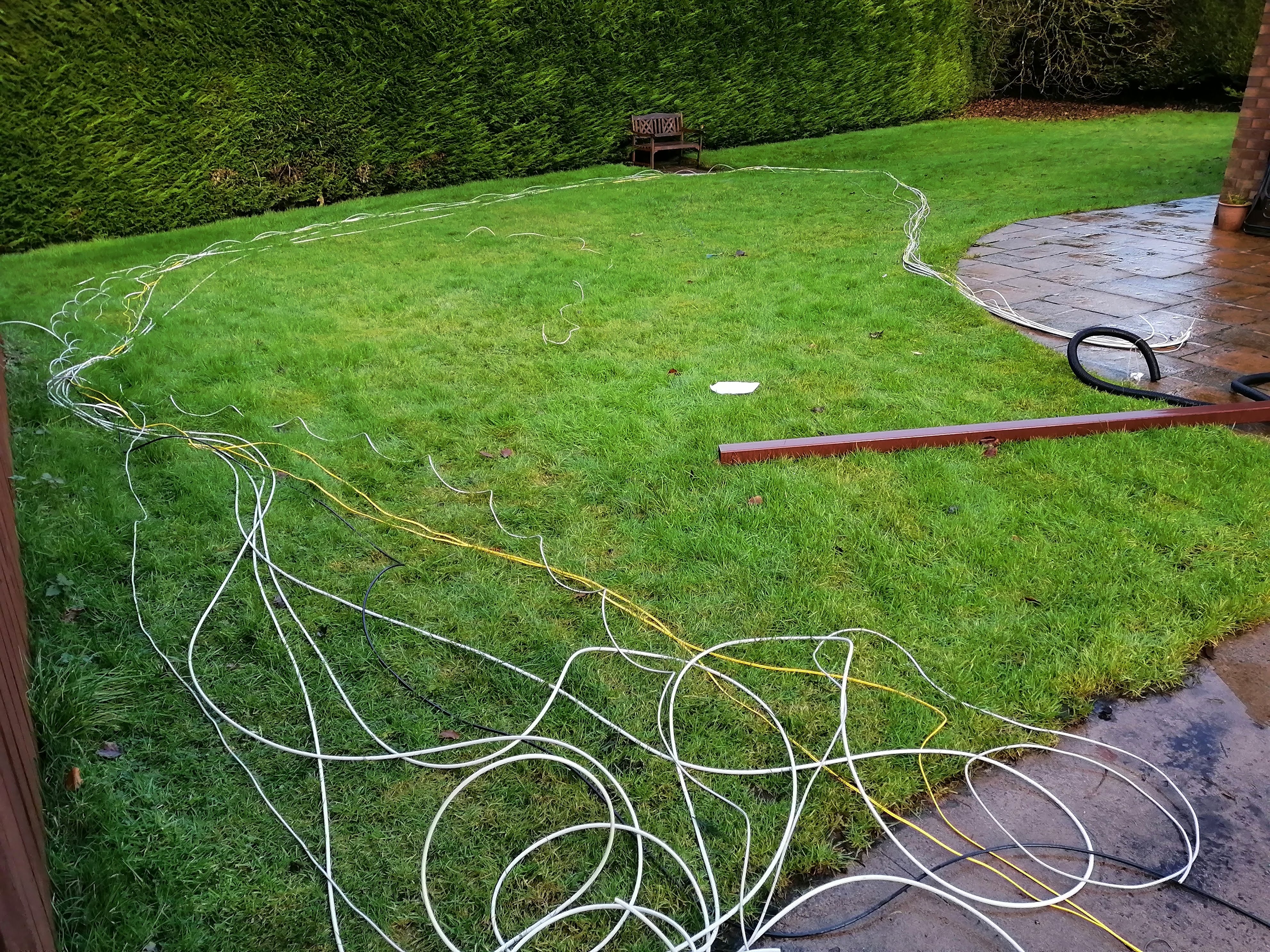 cables layed out across the garden, with the flexible conduit sticking out of the ground